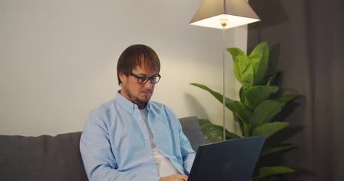 Man Using Laptop on Couch at Home