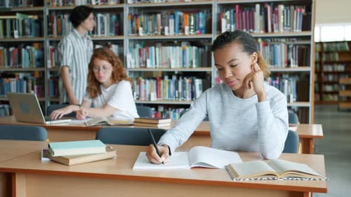 Group of Students Working in Library Reading Books Writing Studying Indoors
