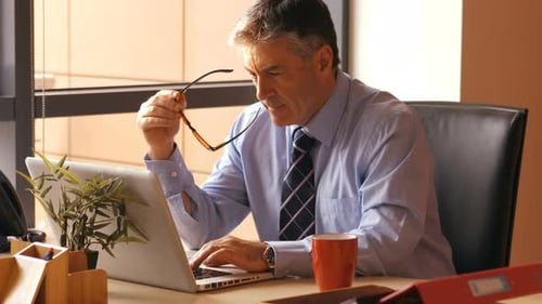 Man Works At Laptop in Office Setting