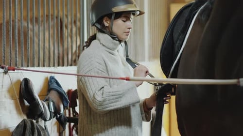 Femme attachant des sangles en selle à cheval