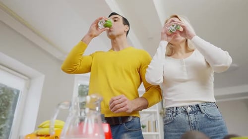 Bottom Angle View of Fit Healthy Young Couple Drinking Healthful Green Smoothie at Home in the