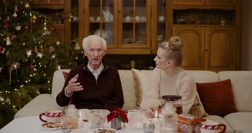 Woman Speaking with Senior by Christmas Tree