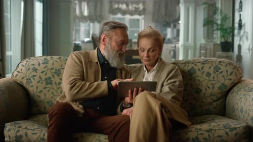 Mature Couple Relaxing on Sofa with Tablet