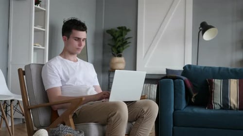 Young Adult Using Laptop in Comfortable Armchair