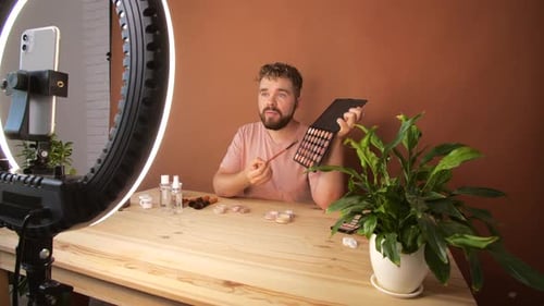 Joven filmando su episodio de videoblog sobre nuevos productos cosméticos mientras