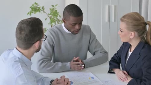 Three People Meeting in an Office to Discuss Data