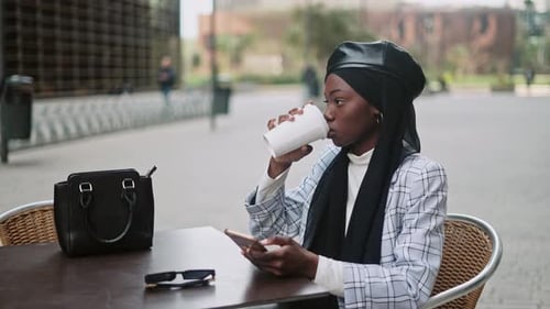 Muslim Female Using Cellphone in Street Cafeteria