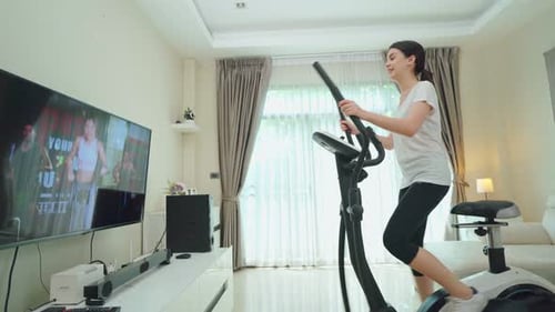 Ejercicio deportivo asiático para mujeres, use una bicicleta estática, siga las instrucciones del entrenador en línea en casa.