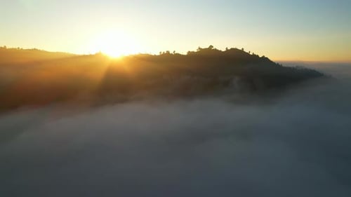 Vue aérienne 4K volant dans le brouillard. Le soleil est caché derrière les nuages au coucher du soleil dans le brouillard.