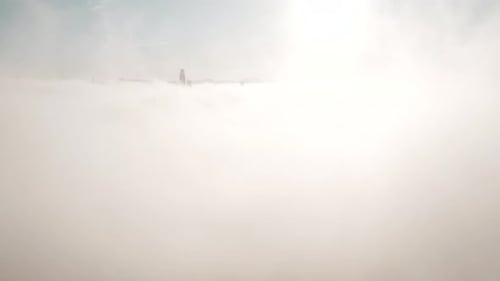 Aerial View of City Buildings Above Dense Cloud