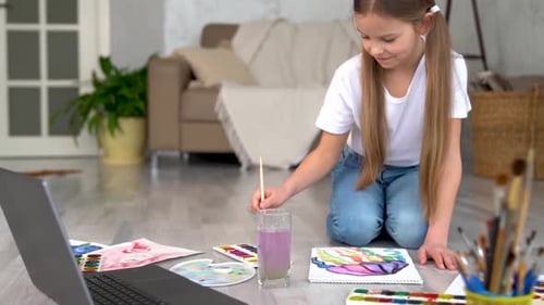Young Girl Painting with Watercolors on Floor