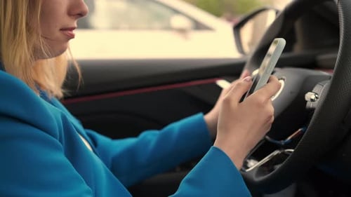 Side View of Businesswoman Sitting in the Car and Using Her Mobile Phone