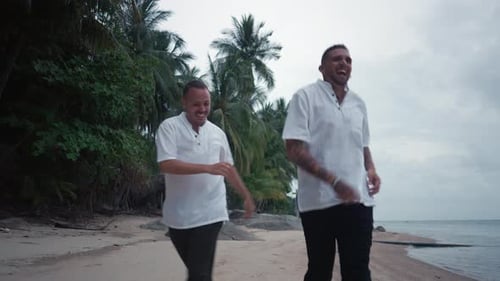 Alegre casal homossexual sorridente correndo em uma praia tropical