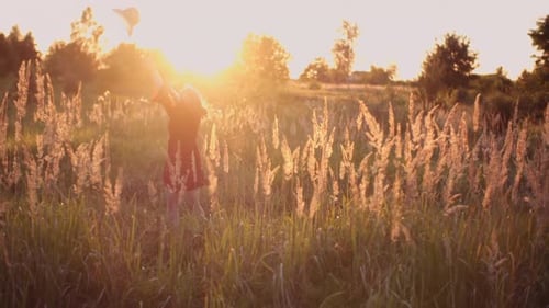 Woman Tosses Hat in Sunset Field
