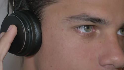 Ein inspirierter Youngman mit Kopfhörern, der Musik aus nächster Nähe genießt.