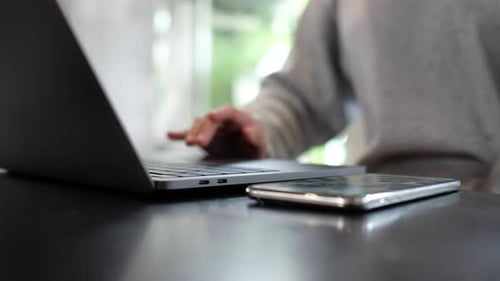 Nahaufnahme einer Frau, die am Laptop, Computer, Touchpad und Handy auf dem Tisch arbeitet und berührt