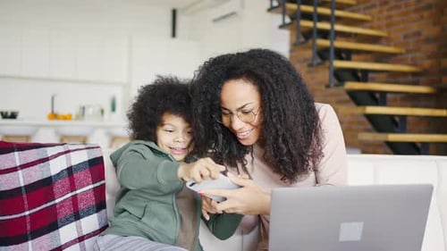 Mother and Child Enjoying Smartphone on Sofa