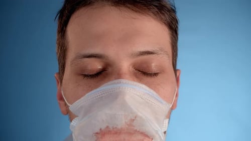Person Puts on Medical Mask with Red Spots