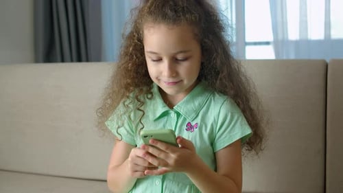 Girl Using Mobile Phone on Couch Indoors