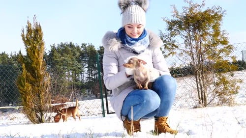Woman Cuddling Adorable Dog in Snowy Winter Landscape