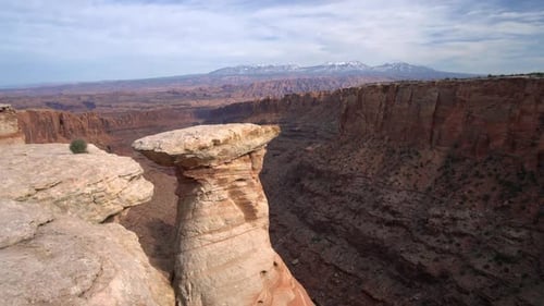 Walking along steep cliff edge viewing rock spire in Long Canyon