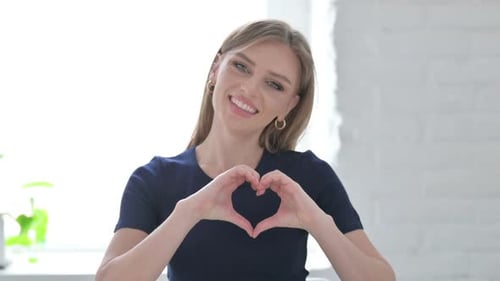 Young Woman Makes Heart Shape With Hands Smiling