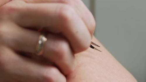 Woman Removes Arm Hair with Tweezers Close Up