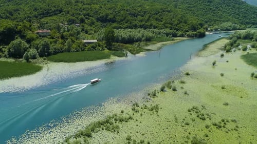 Motorboot schwimmt auf einem Fluss Crnojevica, umrahmt von Seerosen