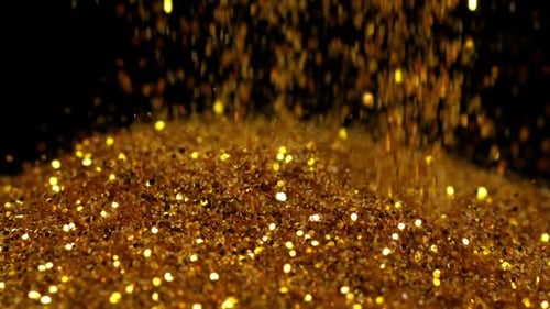 Goldpulver fällt auf schwarzen Hintergrund, Zeitlupe