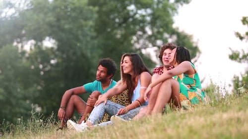 Group of friends sitting on grass having a good time