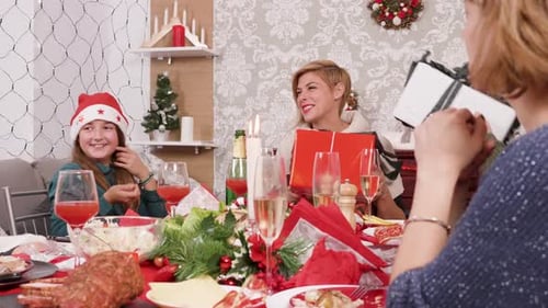 Family and Friends Exchanging Christmas Gifts at Table