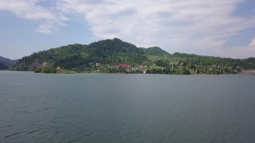 Aerial Panning Shot of Lake in Valley with trees and blue skies