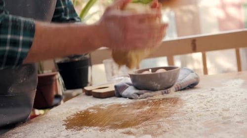 Man Kneading Dough on a Floury Wooden Table