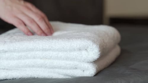 Smoothing Stack of Clean White Towels in Bedroom