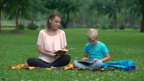 Woman and Child Enjoying Reading, Tablet in Park