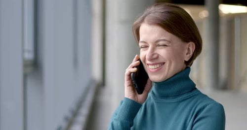 Happy young woman talking on a cell phone in the office.