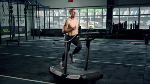 Muscular Man Running on Treadmill at Gym