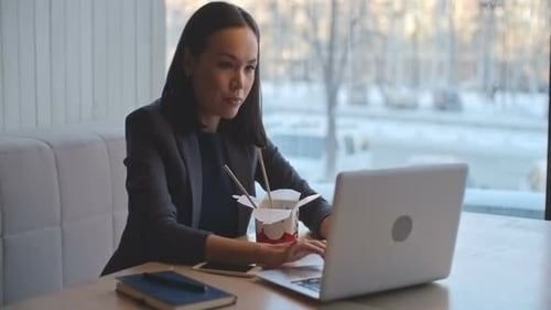 Woman Works on Laptop While Eating Asian Food