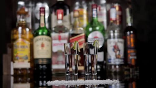 Closeup of a Man and a Woman Taking Shots of Tequila with Lime and Salt in a Bar