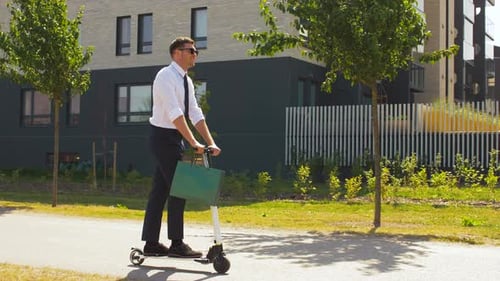 Empresario con bolsa de compras montando scooter