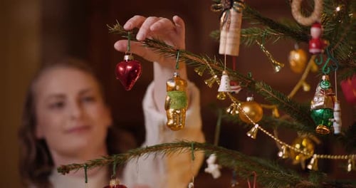 Woman Decorates Christmas Tree with Vintage Ornaments