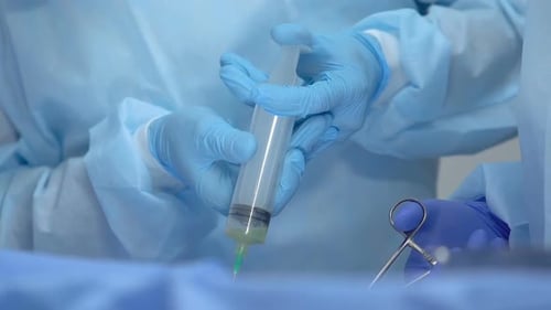 Gloved Hands Preparing Syringe in Surgery