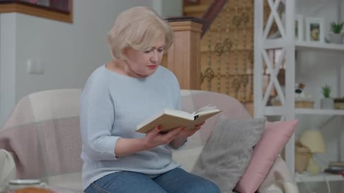 Mature Woman Reading Book on Couch Indoors
