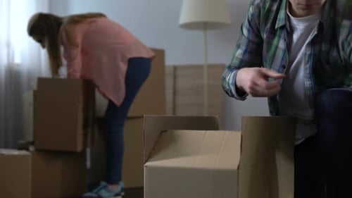 Couple Packing Belongings into Moving Boxes at Home