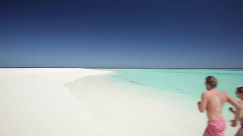 Back View of Running Couple on Sandy Beach