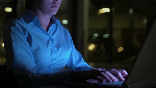Business Woman Typing Laptop at Night in Office, Lighted by Computer Screen