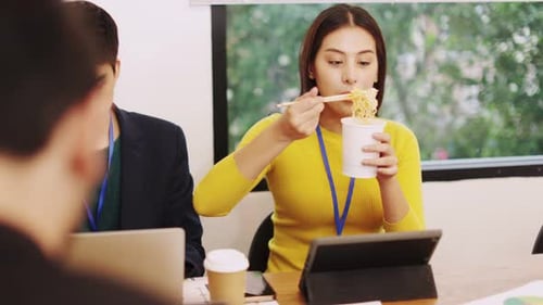 Woman Eating Noodles at Workplace Meeting