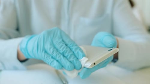 Slow Motion of Female Hands Wiping Smartphone with Tissue and Sanitizer in Office