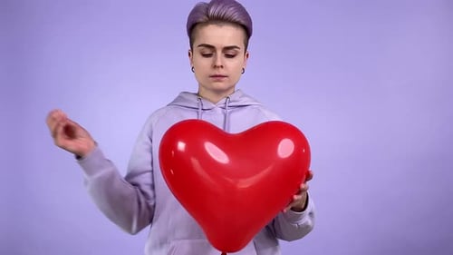 Woman Releases Red Heart Balloon on Lavender Background