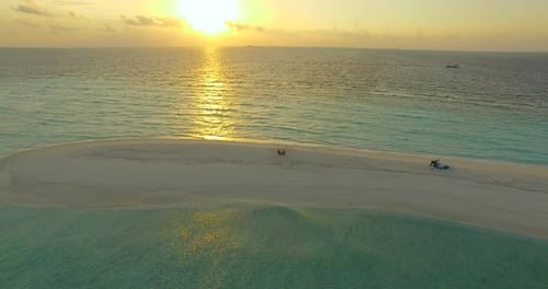 Aerial drone view of a man and woman eating dinner and dining on a tropical island beach